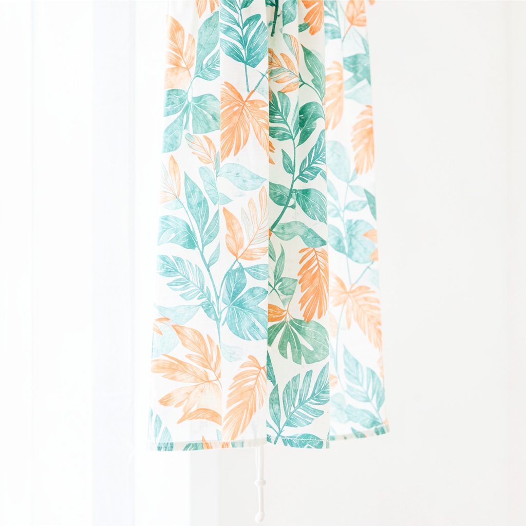 Soft daylight photograph of a pale leaf-patterned textile in teal and green hanging against a bright white background