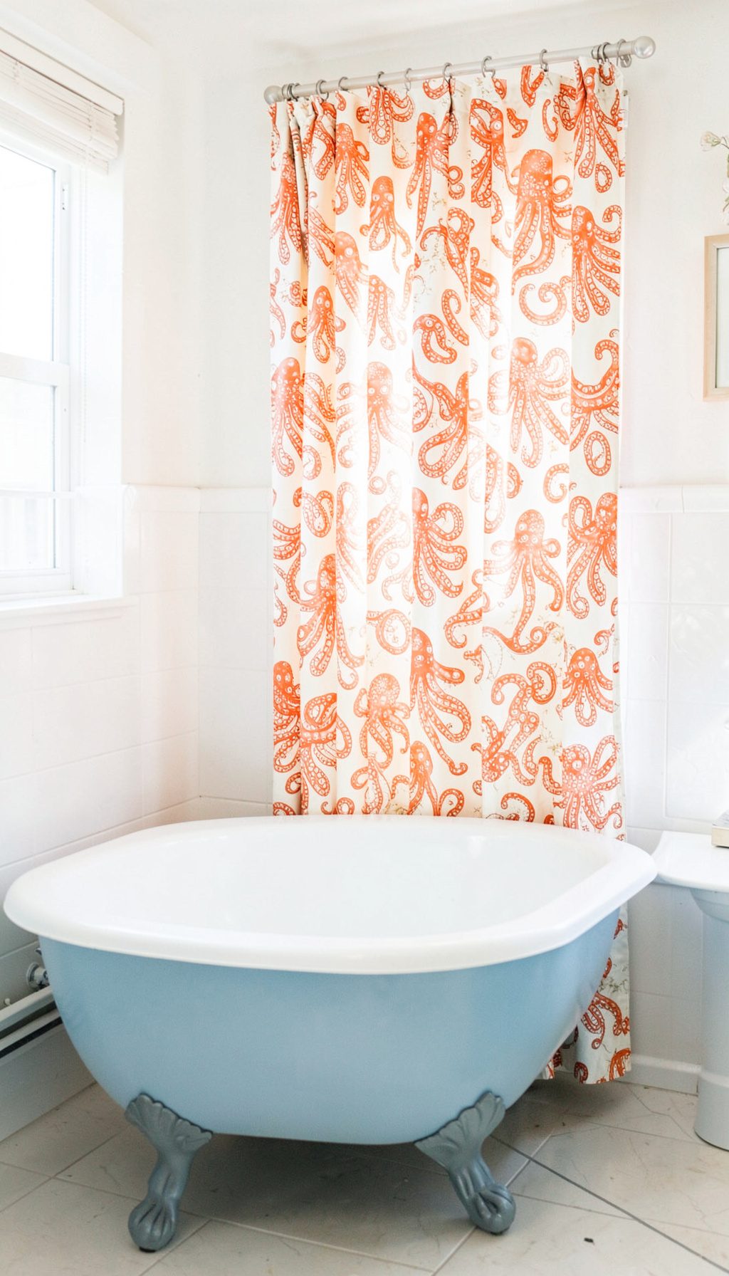 Bathroom with a clawfoot tub dressed in blue, cream and orange patterned curtains with an octopus design